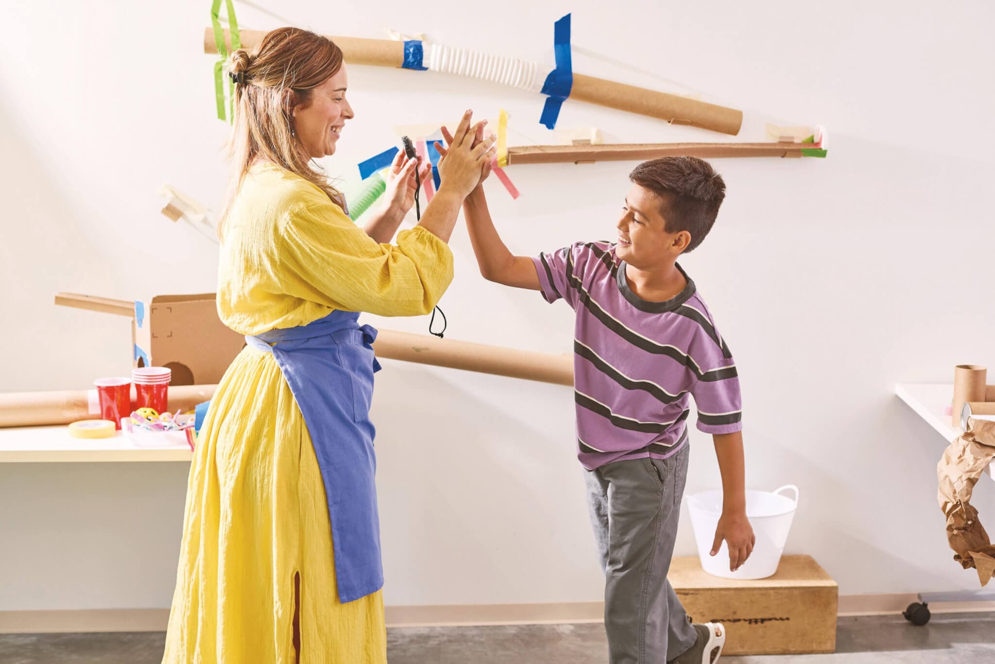 A woman and child create a ball run using recycled and repurposed materials.